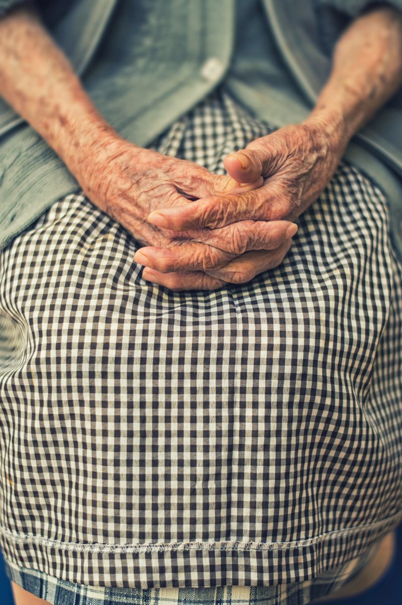 Close up of old woman's hands folded on lap.